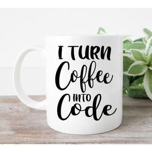May include: A white ceramic mug with a handle on the left side, featuring the black printed text I TURN Coffee INTO Code. The mug has a smooth, glossy finish and a cylindrical shape, standing upright with the text clearly visible on the front surface.