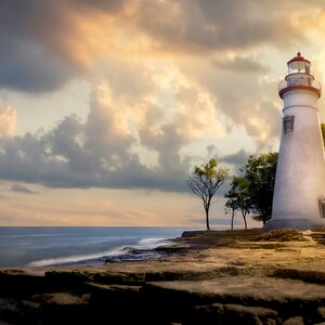 May include: A white lighthouse with a red roof stands on a rocky shore. The lighthouse is tall and slender, with a small window on each side. The sky is cloudy and the water is calm.