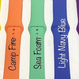 May include: Seven different colored silicone watch bands with white text. The colors are cardinal red, lemon yellow, camp fire, sea foam, light navy blue, sangria, and hot pink. The text on the bands reads: Cardinal Red, Lemon Yellow, Camp Fire, Sea Foam, Light Navy Blue, Sangria, and Hot Pink.