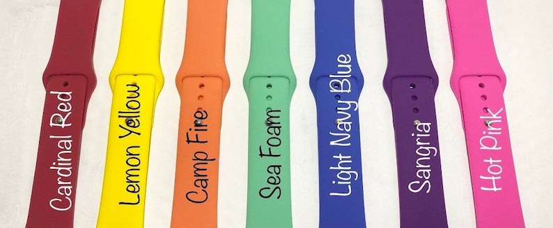May include: Seven different colored silicone watch bands with white text. The colors are cardinal red, lemon yellow, camp fire, sea foam, light navy blue, sangria, and hot pink. The text on the bands reads: Cardinal Red, Lemon Yellow, Camp Fire, Sea Foam, Light Navy Blue, Sangria, and Hot Pink.