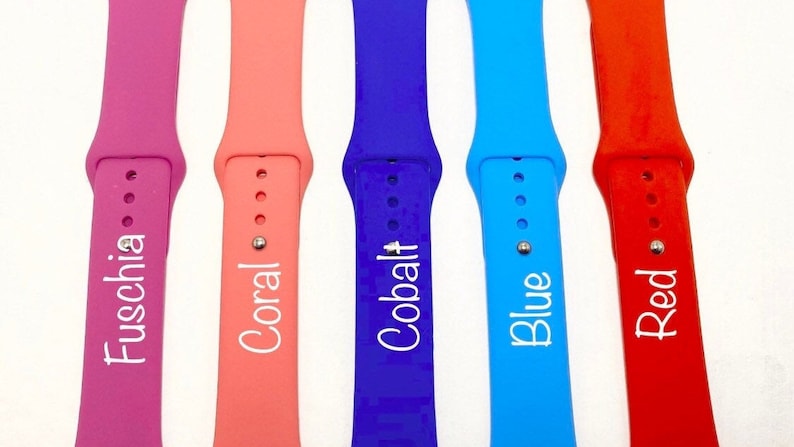May include: Five different colored silicone watch bands with white text. The bands are fuchsia, coral, cobalt blue, blue, and red. The text on the bands reads "Fuschia", "Coral", "Cobalt", "Blue", and "Red".