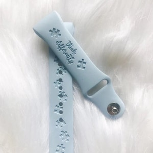 May include: A light blue silicone watch band with the text "Think Differently" and a puzzle piece design. The band has a silver metal buckle.