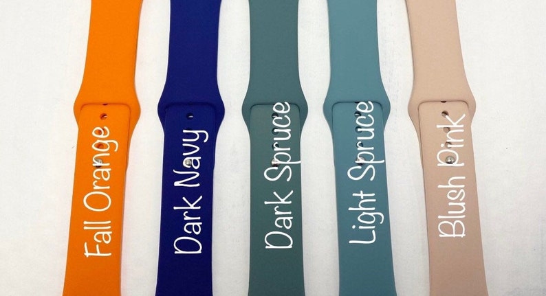 May include: Five different colored silicone watch bands. The bands are labeled "Fall Orange", "Dark Navy", "Dark Spruce", "Light Spruce", and "Blush Pink".