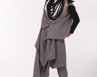 May include: A gray outfit consisting of a long vest with black sleeves, matching pants, and a black scarf. The outfit is paired with black sneakers with white soles. The overall style is modern and minimalist.