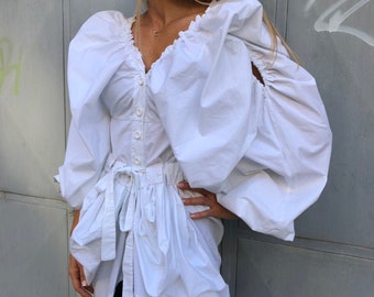 Blusa asimétrica con mangas abullonadas: una blusa extravagante de algodón blanco.