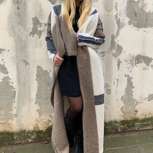 May include: A long, brown and white striped cardigan with a loose fit. The cardigan is made of a soft, fuzzy material and has a shawl collar.