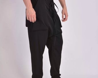 Può includere: Pantaloni neri con vita con coulisse e ampie tasche. I pantaloni sono abbinati a scarpe da ginnastica bianche. Lo stile è casual e moderno. I pantaloni sono realizzati in un tessuto morbido e fluido.