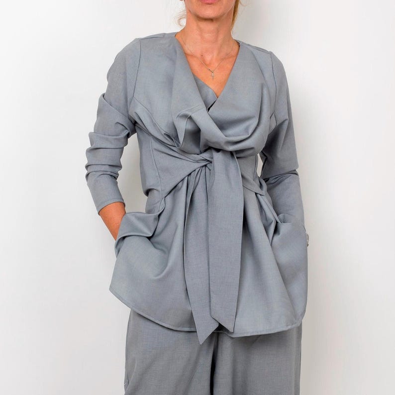 May include: A gray wrap top with a long sleeve and a tie at the waist.