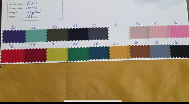 May include: A fabric swatch card with various color samples. The card includes a range of colors, from deep blue to pink, with a white background. The fabric is 155cm wide and made of 100% PL.