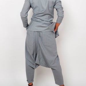 May include: A gray, long-sleeved shirt and matching pants with a loose, flowing fit. The pants have a unique design with a gathered crotch and a drawstring.
