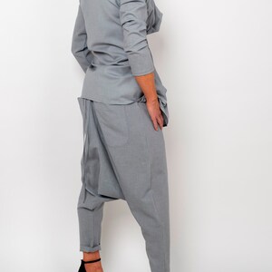 May include: A gray, loose-fitting, long-sleeved top with a draped neckline and a pair of gray, loose-fitting,  harem-style pants. The pants have a gathered detail at the crotch and a wide leg.