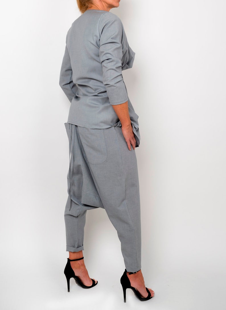 May include: A gray, loose-fitting, long-sleeved top with a draped neckline and a pair of gray, loose-fitting,  harem-style pants. The pants have a gathered detail at the crotch and a wide leg.