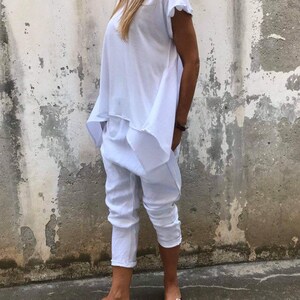 Puede incluir: Una blusa blanca holgada de manga corta y un pantal&oacute;n blanco. El pantal&oacute;n tiene pierna ancha y est&aacute; cortado en el tobillo. La persona lleva sandalias marrones oscuras.