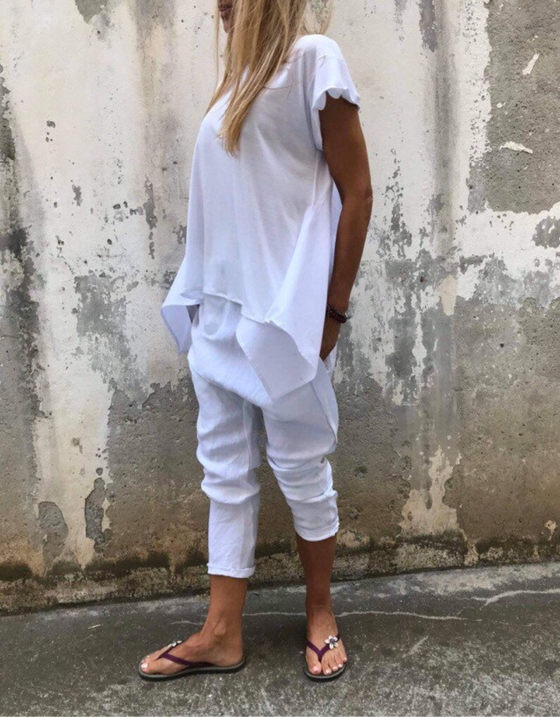 Puede incluir: Una blusa blanca holgada de manga corta y un pantal&oacute;n blanco. El pantal&oacute;n tiene pierna ancha y est&aacute; cortado en el tobillo. La persona lleva sandalias marrones oscuras.
