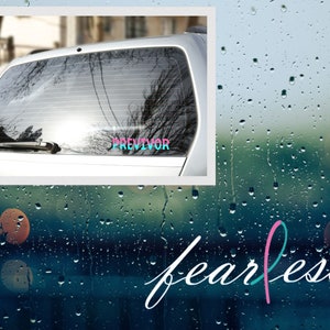 May include: A car window sticker with the word "PREVIVOR" in a colorful gradient, set against a blurred background of a car and trees. The word "fearless" is written in cursive with a pink and teal ribbon.