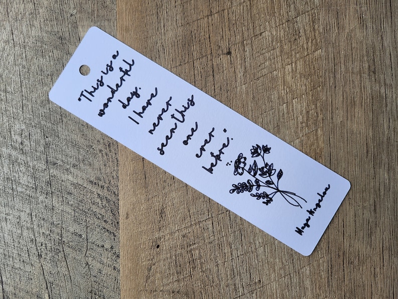 Puede incluir: Marcador blanco con letras en tinta negra que dice "This is a wonderful day. I have never seen one this better..." con una ilustraci&oacute;n floral negra y el nombre "Maya Angelou" en la parte inferior.