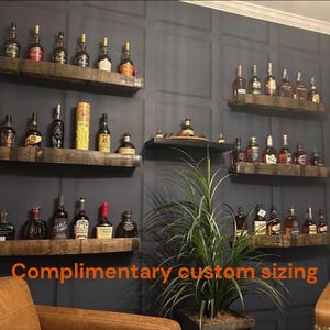 May include: Wooden shelves displaying a collection of liquor bottles against a dark gray wall. The shelves are made of reclaimed wood. The text "Complimentary custom sizing" is visible at the bottom of the image.