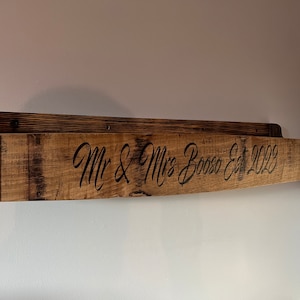 Pu&ograve; includere: Un ripiano in legno realizzato con una botte di vino riciclata con accenti in metallo. Il ripiano &egrave; inciso con il testo "Mr & Mrs Bosso Est 2023".