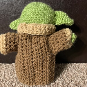 Peut inclure: Un jouet en peluche crochet&eacute; en forme de personnage de la franchise Star Wars. Le jouet porte un pull marron et un chapeau vert.