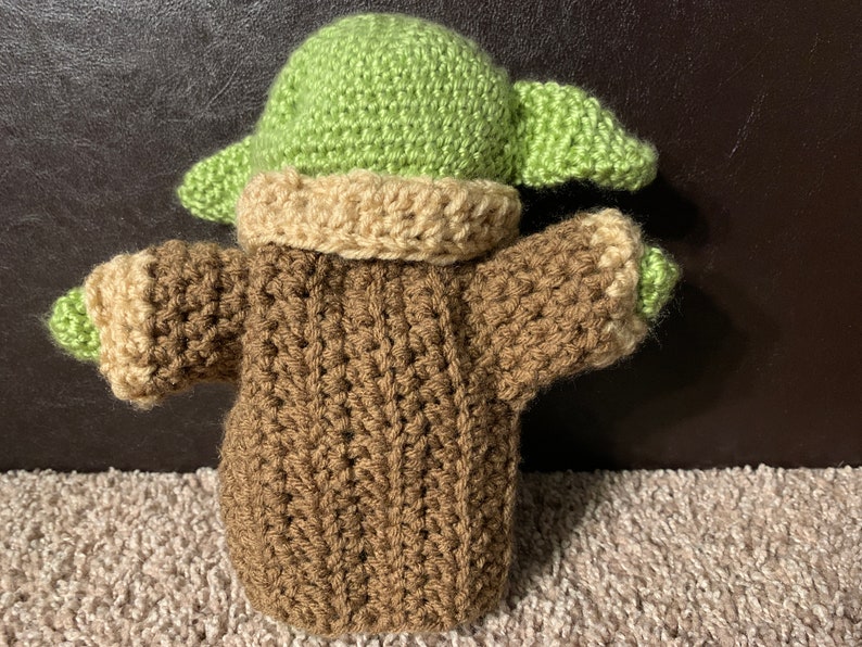 Peut inclure: Un jouet en peluche crochet&eacute; en forme de personnage de la franchise Star Wars. Le jouet porte un pull marron et un chapeau vert.