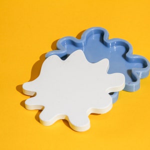 May include: Two silicone molds in the shape of a cloud. The top mold is blue and the bottom mold is white.
