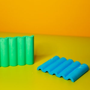 Puede incluir: Dos juegos de bloques de construcci&oacute;n de pl&aacute;stico de colores. Un juego es verde y el otro es azul. Los bloques tienen forma de techo ondulado.