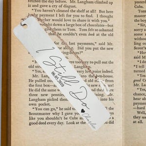 May include: A personalized metal bookmark with the words "I Still Do" and the date "06.05.2010" in elegant script. A small heart and the name "Charlie" are also included. The bookmark hangs from a delicate chain.