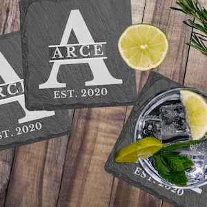 May include: Three black slate coasters with white lettering. Each coaster features a large white letter "A" with the name "ARCE" and "EST. 2020" written below.