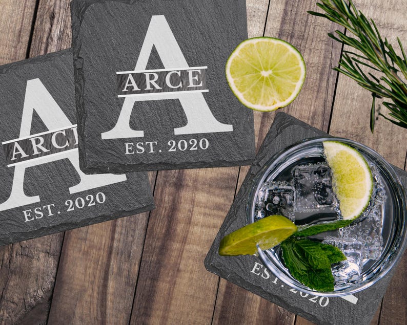 Laser-engraved personalized slate coasters set of four from ScratchThatEtch, showing a family name engraved in bold text on natural dark grey stone
