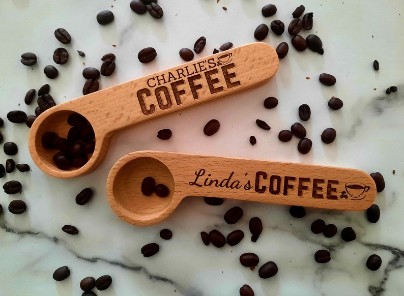 May include: Two wooden coffee scoops with engraved text. The top scoop says "Charlie's Coffee" and the bottom scoop says "Linda's Coffee". Both scoops have a small coffee cup icon engraved on them.