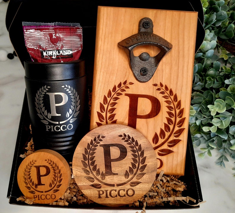 May include: A gift set featuring a personalized wooden bottle opener, a personalized wooden coaster, and a personalized stainless steel tumbler. The bottle opener has a metal bottle opener attached to it. The coaster and tumbler both have the letter "P" and the word "PICCO" engraved on them.