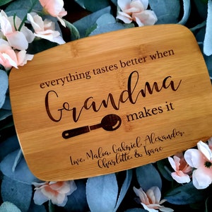 May include: A light brown wooden cutting board with the text "everything tastes better when Grandma makes it" engraved on it. The board also has a small spoon design and the names "Maloa, Gabriel, Alexander, Charlotte & Isaac" engraved on it.
