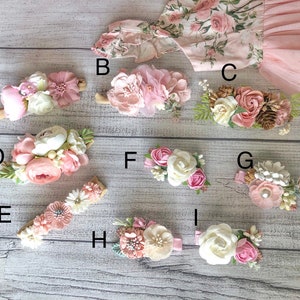 Op de afbeelding: Negen verschillende bloemenhaarclips met roze, witte en cr&egrave;mekleurige bloemen. De clips zijn gerangschikt op een houten oppervlak.
