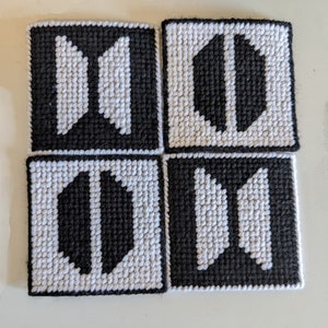 May include: Four black and white square coasters with a geometric design. The coasters are made of fabric and have a woven texture.