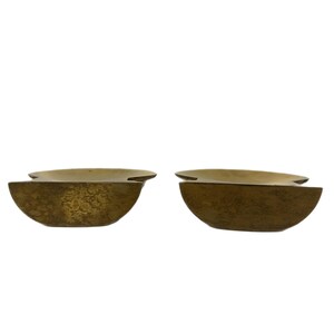 May include: Two brass-colored, semi-circular decorative bowls. Each bowl has a textured surface and a flat, horizontal top. The bowls are positioned side-by-side against a white background.