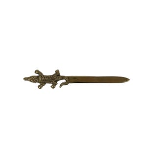 May include: A brass letter opener with an alligator motif. The alligator is at the top of the opener, with a long, flat blade extending from its body. The opener is approximately 23 cm long.