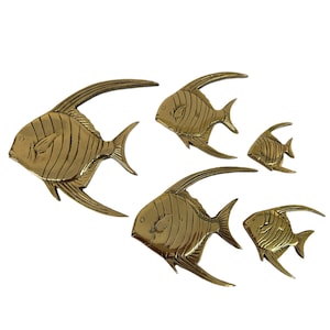 Könnte beinhalten: Fünf Wanddekorationen aus Messing in Form von Fischen. Die Fische haben detaillierte Flossen und Schuppen in verschiedenen Größen. Der größte Fisch ist etwa 30 cm lang, der kleinste etwa 15 cm. Auf weißem Hintergrund angeordnet.