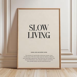 May include: A beige poster with black text that reads "SLOW LIVING DOING LESS AND BEING MORE The practice of intentionally embracing a slower, more mindful pace of life that creates space for stillness, reflection, and meaningful experiences. Step away from the constant rush, let go of distractions, and cultivate a deeper connection with yourself, others, and the world around you."