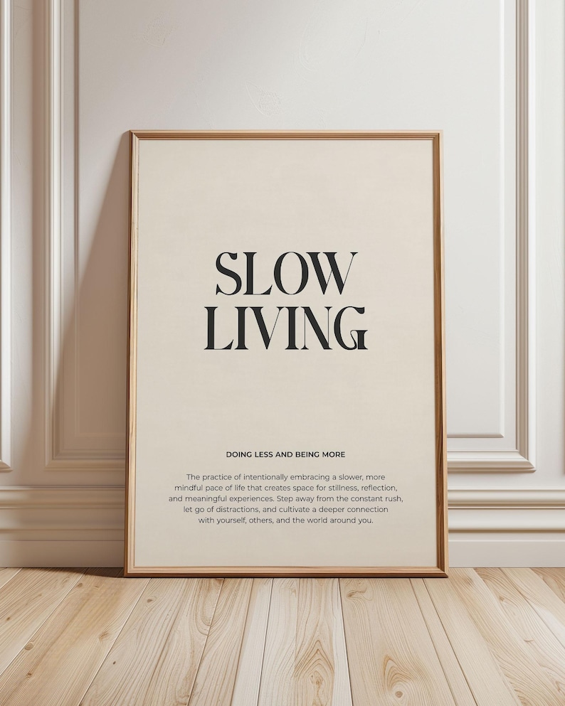 May include: A beige poster with black text that reads "SLOW LIVING DOING LESS AND BEING MORE The practice of intentionally embracing a slower, more mindful pace of life that creates space for stillness, reflection, and meaningful experiences. Step away from the constant rush, let go of distractions, and cultivate a deeper connection with yourself, others, and the world around you."