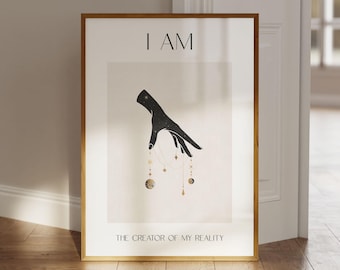 Puede incluir: Un póster minimalista con una mano negra sosteniendo cuerpos celestes dorados. El texto "I AM THE CREATOR OF MY REALITY" está impreso debajo de la imagen.