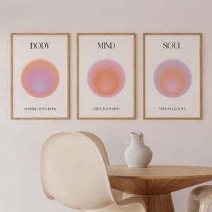 Könnte beinhalten: Drei gerahmte Drucke mit einem Farbverlaufskreisdesign in Rosa, Orange und Lila. Die Drucke haben die Wörter "BODY", "MIND" und "SOUL" oben und die Sätze "Nähr deinen Körper", "Öffne deinen Geist" und "Nähr deine Seele" unten.