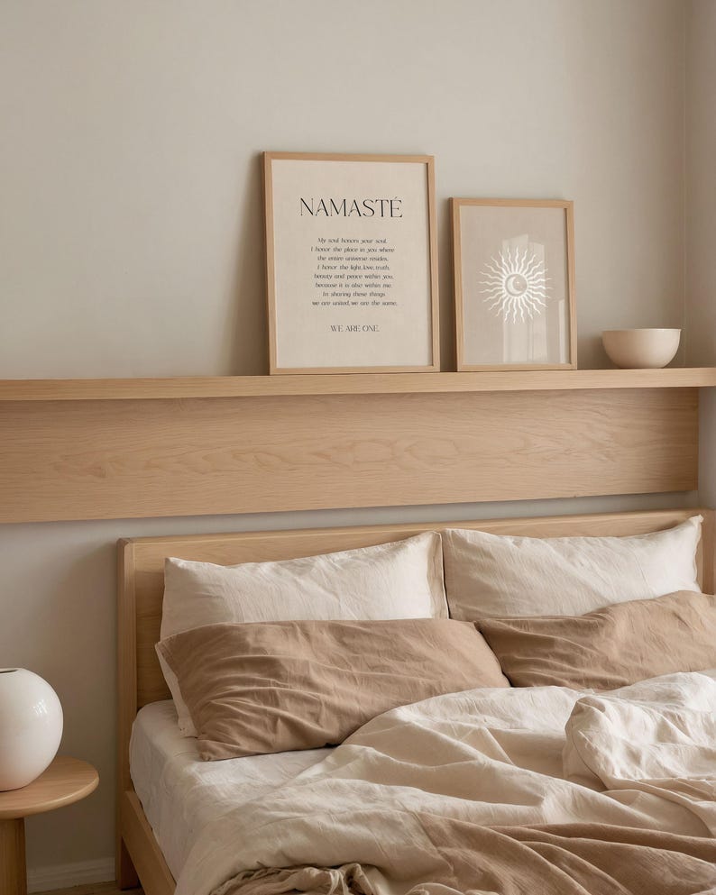 K&ouml;nnte beinhalten: Ein Schlafzimmer mit einem Bett mit beiger und wei&szlig;er Bettw&auml;sche, einschlie&szlig;lich Kissen und einer Bettdecke. &Uuml;ber dem Bett zeigt ein Holzregal zwei gerahmte Drucke mit Text und einem Sonnendesign sowie eine kleine wei&szlig;e Sch&uuml;ssel.