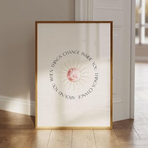 May include: A framed print with a pink sun and gold rays. The text reads "When things change inside you, things change around you."