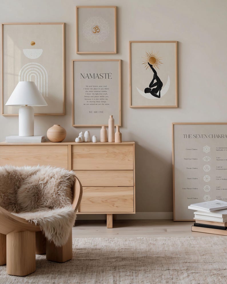 K&ouml;nnte beinhalten: Eine ruhige Innenszene mit gerahmten Kunstdrucken, einer Holzkommode und einem modernen Stuhl mit einem Kunstfell&uuml;berwurf. Die Kunstwerke umfassen abstrakte Designs und Yoga-Illustrationen. Eine wei&szlig;e Lampe und dekorative Holzobjekte erg&auml;nzen die beruhigende &Auml;sthetik.