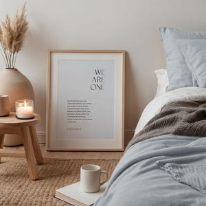 May include: A framed print with the text "WE ARE ONE" and a poem about the soul and the universe. The print is hanging on a wall in a bedroom with a bed and a rug.