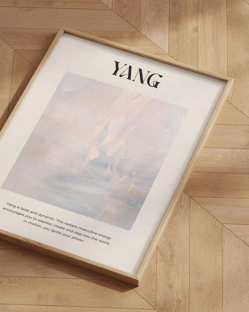 Op de afbeelding: Een ingelijste kunstdruk met het woord "YANG" in zwart bovenaan. Het kunstwerk heeft een zacht, abstract ontwerp in pastelkleuren. Tekst eronder beschrijft de energie van Yang. De lijst is lichtgekleurd hout.
