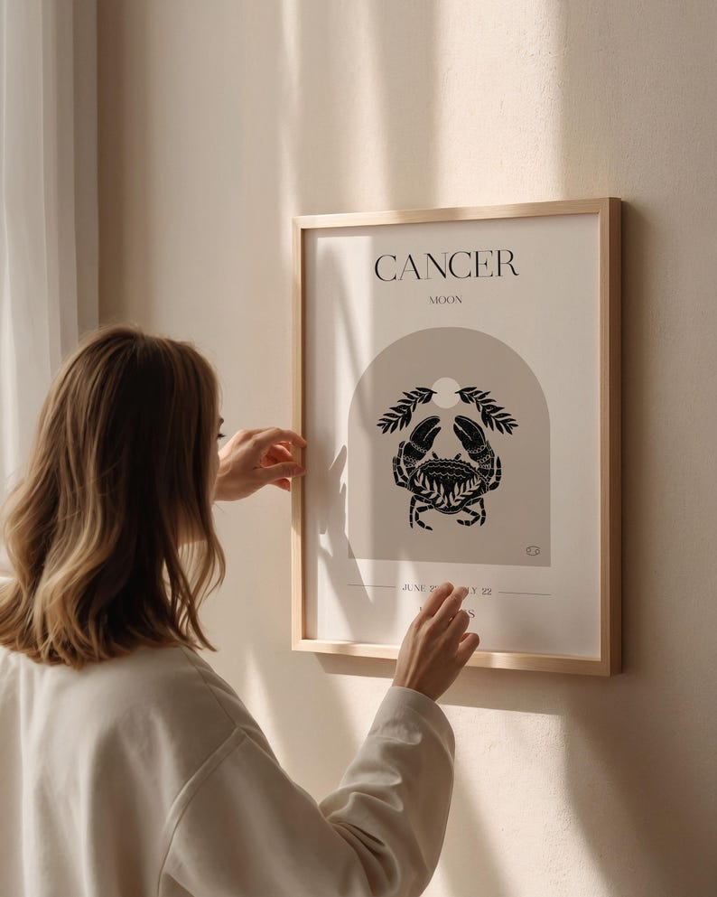 May include: A framed print with a minimalist design featuring the astrological sign Cancer, represented by a crab, with the text "Cancer Moon" above the image.