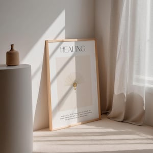 May include: A framed print with the word "HEALING" in black text on a beige background. The print features a gold sunburst design with a quote about healing. The print is leaning against a white wall.