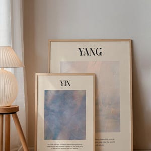 Op de afbeelding: Twee ingelijste kunstdrukken met de woorden "Yin" en "Yang" in zwarte tekst. De "Yin" print heeft een blauw en roze abstract ontwerp. De "Yang" print heeft een beige en roze abstract ontwerp. Beide zijn in lichte houten frames.