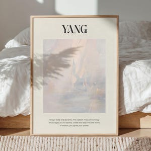 Op de afbeelding: Een ingelijste print met het woord "YANG" in zwart bovenaan. Het kunstwerk heeft een zacht, abstract ontwerp in tinten perzik, blauw en wit. De tekst hieronder beschrijft de energie van Yang. De lijst is licht van kleur.